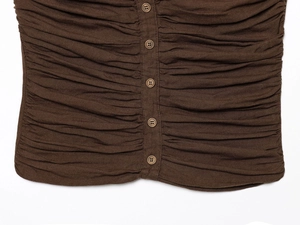 Close-up of brown ruched fabric detailing with vertical buttons on a women's top