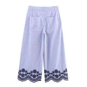 Detail of blue striped wide-leg pants featuring floral embroidery and scalloped hem