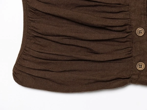 Detail of ruched dark brown fabric texture and wooden buttons on summer slim strapless top