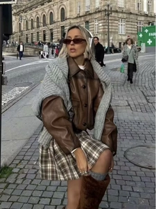 Street style vintage brown faux leather jacket with knitted sweater and plaid skirt