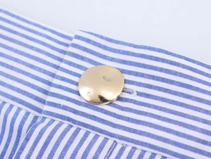 Detailed macro view of gold button on blue and white striped fabric waistline
