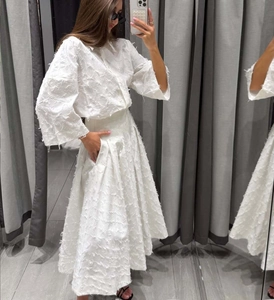 Vue détaillée d'une chemise blanche et d'une jupe midi avec texture à franges unique