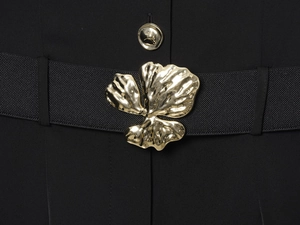 Détail de la ceinture élastique noire avec boucle florale dorée et bouton décoratif