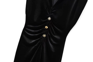 Detail eines schwarzen Samtkleides mit goldenen Vintage-Knöpfen und gerafftem Stoff