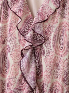Detailed macro view of paisley floral print fabric with purple ruffled decorative edges