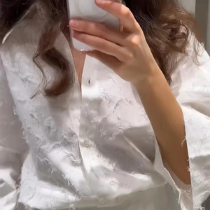 Détail d'une chemise blanche à manches longues avec texture 3D plume et tissu à glands