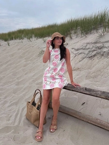 Detail of a white sleeveless mini dress with pink floral print and a casual beach aesthetic