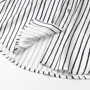 Close-up of striped satin shirt hem featuring a detailed gold relief decorative button