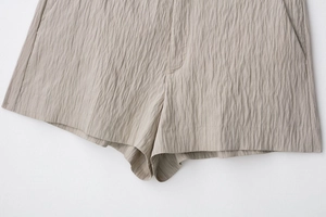 Close-up of beige summer shorts featuring pleated vertical texture and neat stitching