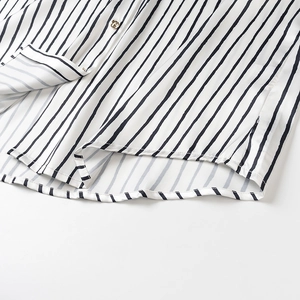 Detail of pinstripe satin shirt hem featuring elegant golden buttons and smooth texture