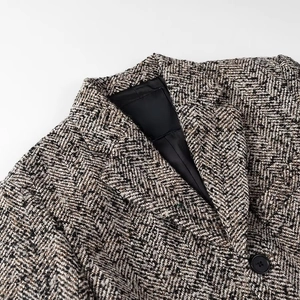 Close-up of gray herringbone tweed blazer showing lapel detail and black button