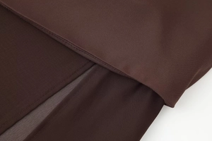 Detail shot of dark brown dress fabric showing precise stitching and hemline texture