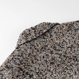 Detail of grey herringbone tweed blazer showing premium wool blend fabric texture