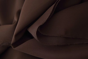 Detailed macro view of double-stitched hem and fine texture on dark brown dress fabric
