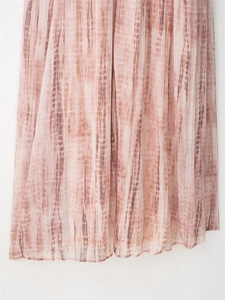 Detailed view of pink tie-dye pleated fabric showing vertical textures and hemline drape