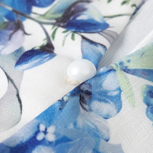 Detailed macro view of the blue floral print fabric with elegant white pearl button closure