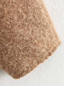 Detailaufnahme der warmbraunen Lammwolltextur einer legeren Strickjacke für Damen