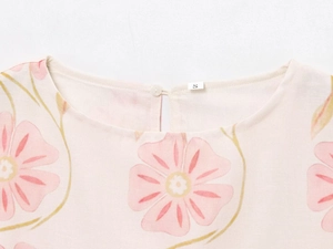 Detailed close-up of floral print dress neckline with button closure and size S label