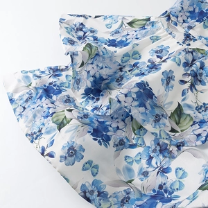 Detailed close-up of blue floral and butterfly print on soft white chiffon fabric