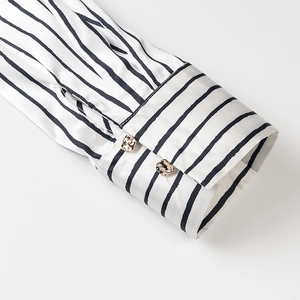Detail of silk-satin striped shirt cuffs with textured golden metal designer buttons