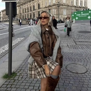 Vintage brown faux leather jacket with plaid mini skirt and plush boots in city street