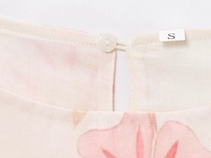Detail of round neckline on floral mini dress with button closure and size S label