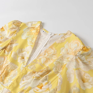 Detail view of yellow floral dress showing V-neckline, puff sleeves and invisible zipper