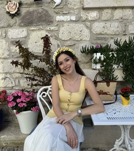 Close-up of yellow knit tank top with square neck and metallic buttons on white skirt