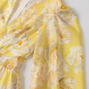 Detail of floral print dress featuring a deep V-neck and an elegant pearl button fastener