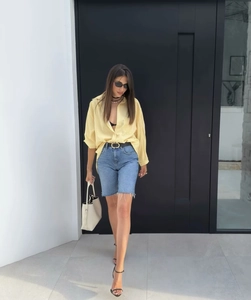 Detail of oversized yellow striped shirt paired with frayed hem denim shorts on a model