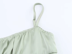 Detail of mint green satin dress showing adjustable spaghetti straps and pleated neckline