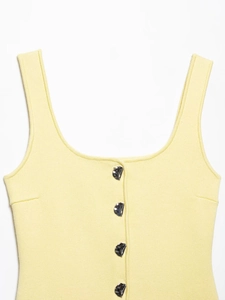 Detail view of light yellow sleeveless knit vest with silver buttons and fine texture