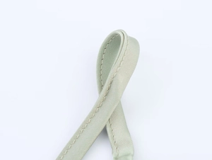 Detail view of sage green satin dress strap with fine twill texture and sturdy stitching