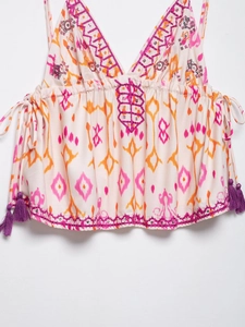 Detail of bohemian camisole showing pink embroidery and colorful sequin floral patterns