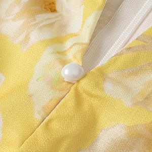 Detail of white pearl button and invisible zipper on yellow floral chiffon dress