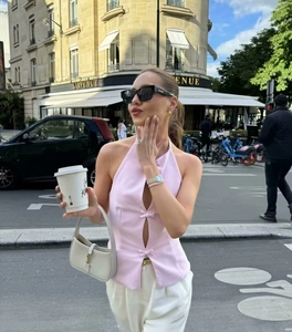 Detailed view of a pink halter top with front slit and bow accents on a city street