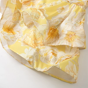 Detailed close-up of yellow floral print dress hem with mesh lining for volume