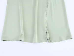 Close-up of mint green satin dress featuring smooth hemline and side slit detail