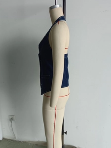 Detail view of denim halter top featuring contrast stitching and metallic buttons