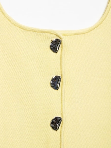 Detail of pale yellow knit cardigan with polished silver pebble-shaped metal buttons