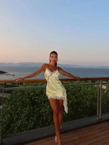 Detailed view of pale yellow satin dress with delicate white lace trim and irregular hemline