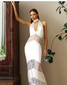 Close-up of elegant white satin dress featuring intricate lace patchwork and halter neck detail