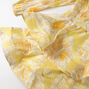Close-up of yellow floral dress featuring detailed butterfly prints and ruffled sleeve hem