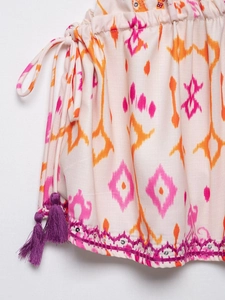 Close-up of bohemian ikat print fabric with purple tassels and silver sequin embroidery