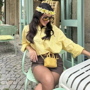 Women's yellow striped long sleeve shirt with brown skirt and luxury style handbag