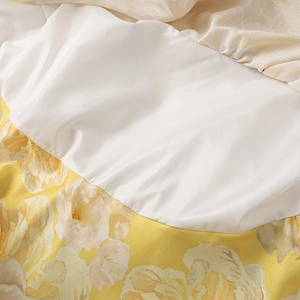 Close-up of yellow floral linen dress fabric showing smooth texture and white lining