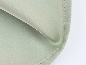 Detail shot of light green satin dress fabric with fine twill texture and neat stitching