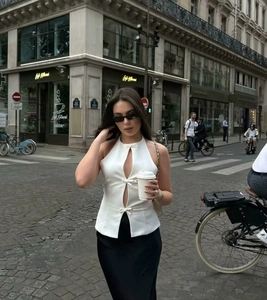 Detail of white halter neck top featuring elegant front bows and vertical cutouts
