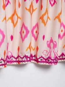 Macro detail of sequin flower embroidery and geometric ethnic patterns on pink fabric