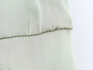 Detailed macro shot of fine stitching on light sage green satin fabric with twill texture